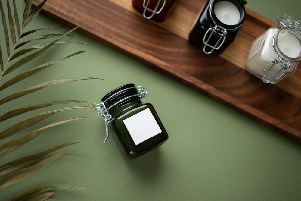 Velas em potes escuros com folhagem tropical